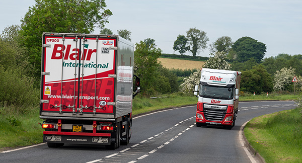 Two Blair International Distribution Trucks Driving Towards Each Other